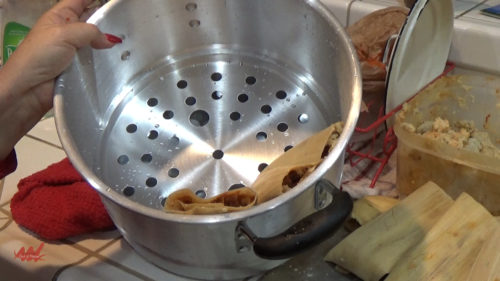 Placing Tamales in a steamer pot.